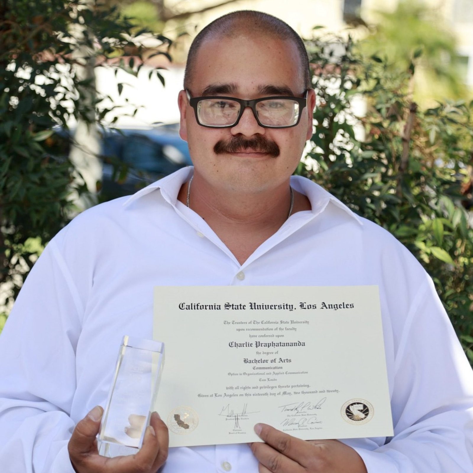 An image of a person formerly sentenced to LWOP holding a certificate and award.