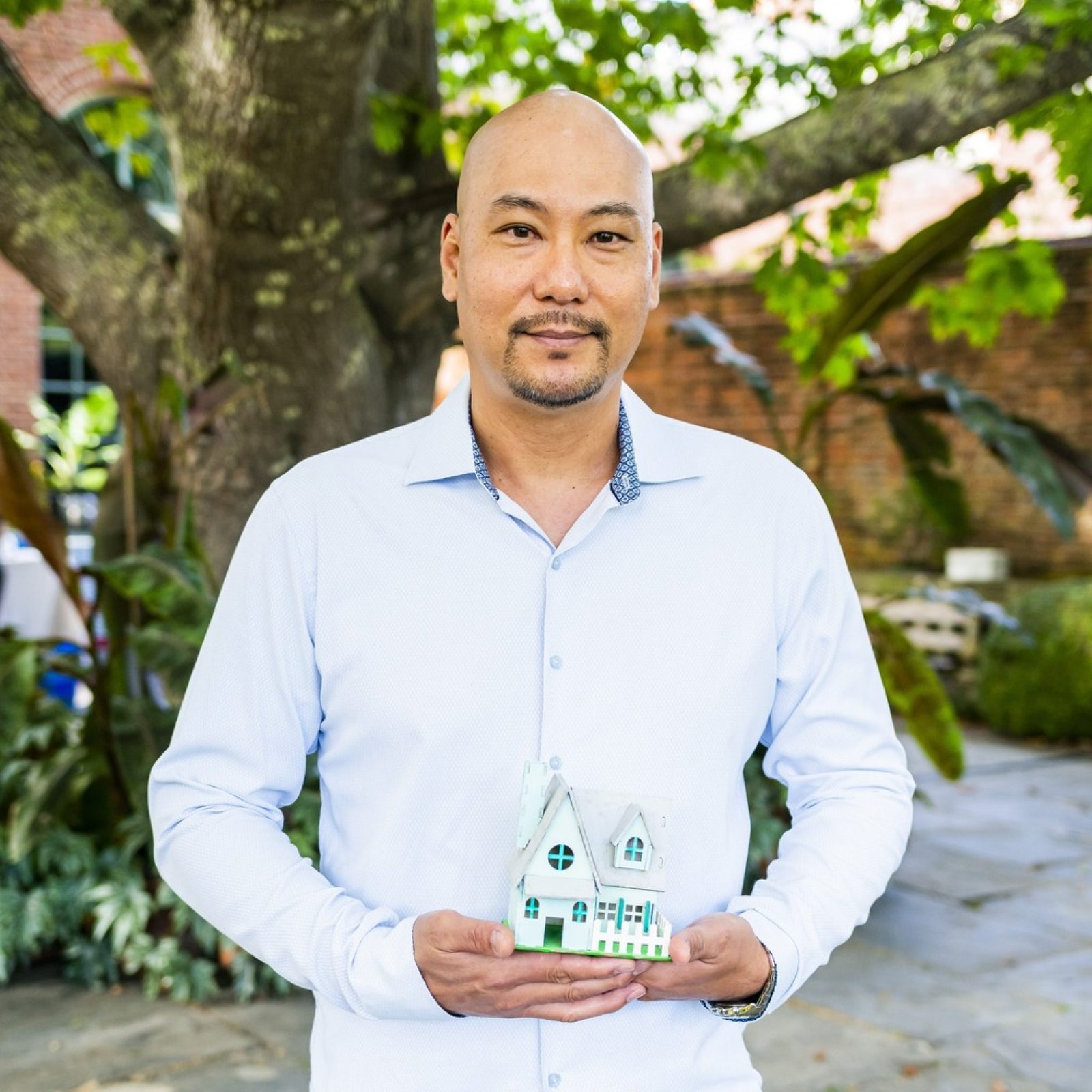 An image of a person formerly sentenced to LWOP holding a miniature house.